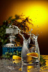 Slice of lemon fall in glass with cocktail, creating beautiful splashes.
