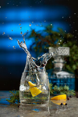 Slice of lemon fall in glass with cocktail, creating beautiful splashes.