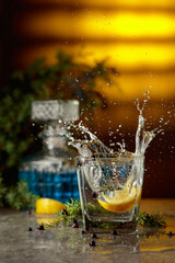 Slice of lemon fall in glass with cocktail, creating beautiful splashes.