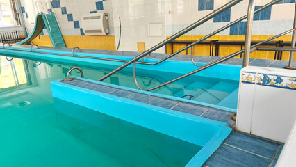 Indoor pool with stainless steel railings, blue water, filled with natural light for exercise, therapy and exciting water activities.