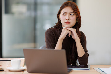 Concerned puzzled asian freelance worker woman looking at laptop with confused hand gesture....