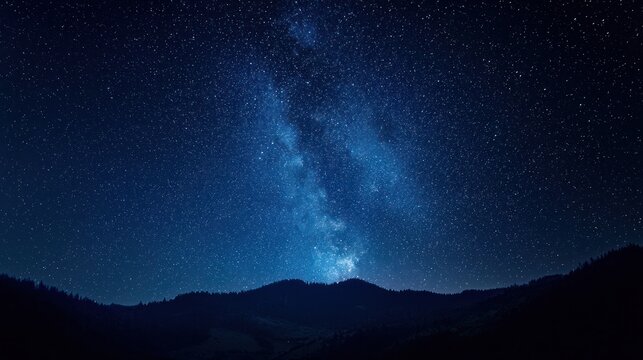 A starry night sky with the Milky Way visible in the distance, silhouetted against the dark blue sky, with mountains in the foreground and a forested area in the background. - Powered by Adobe