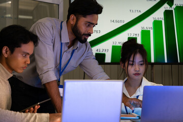 Business team analyzing data on laptops with growth chart in background. Diverse professionals collaborating in office, discussing financial performance, strategy, and success analytics 