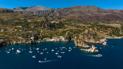 Obraz premium Aerial view of the Bay of Scopello, in the province of Trapani, Sicily, Italy. Boats are on vacation around the rocks in the Zingaro Nature Reserve. 