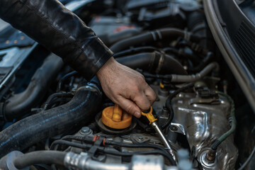 A close-up of a person's hand removing the oil dipstick from the engine. Routine maintenance,...