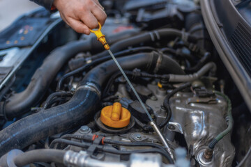 A close-up of a person's hand removing the oil dipstick from the engine. Routine maintenance,...