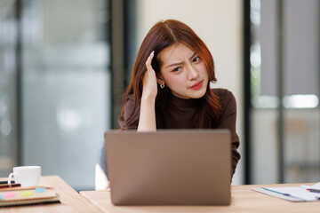 Portrait of young asian business woman are stressed while working on laptop, Tired asian businesswoman with headache at office, feeling sick at work.
