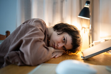 Exhausted burned out woman resting head on hands looking at camera. Tired female working late night desk with stress, mental exhaustion, overtime work stress, depressed female fatigue, overload