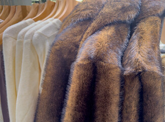Fluffy faux fur winter jackets on a clothes rack in a department store 