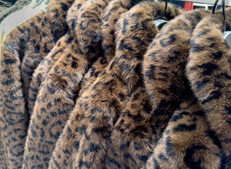 Fluffy faux fur winter jackets on a clothes rack in a department store 