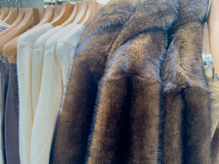 Fluffy faux fur winter jackets on a clothes rack in a department store 