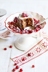 Mini Christmas pudding decorated with fresh cranberries and sugar powder on festive cake stand over white wooden background