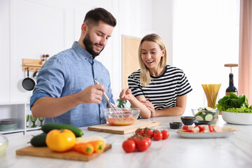 Happy couple cooking together at table in kitchen