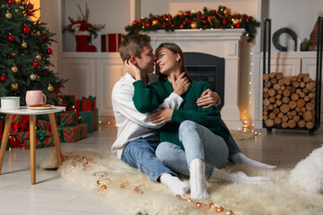 Obraz premium Lovely couple on floor in room decorated for Christmas