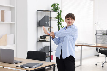 Obraz premium Young businesswoman stretching her arm at table in office