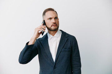 A focused male business professional stands against an isolated colored background. He speaks on a mobile phone, projecting confidence and concern, ready to solve tasks. The scene highlights