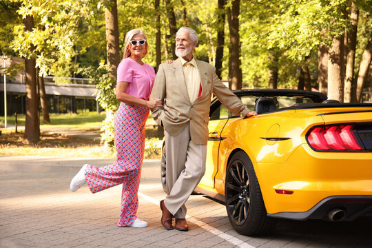 Stylish senior couple near modern cabriolet outdoors - Powered by Adobe