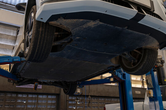 Electric car inspection under chassis on hydraulic lift in auto service center