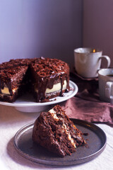 chocolate carrot cake with cream cheese frosting decorate with chocolate ganache and grated chocolate on dark brown ceramic plate