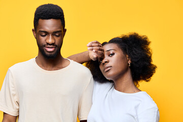 A young African couple in casual clothing expressing confidence against a vibrant yellow background, showcasing modern fashion and emotional connection