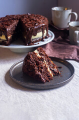 chocolate carrot cake with cream cheese frosting decorate with chocolate ganache and grated chocolate on dark brown ceramic plate