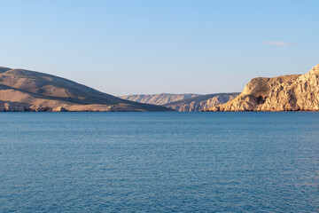 Fototapeta premium Tranquil seascape with rocky hills and clear blue sky at sunrise. View of Prvic island, Croatia