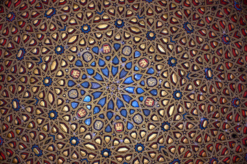 Close-up of the ornate ceiling in the Real Alcázar of Seville, featuring an intricate geometric pattern in gold, blue, and red a masterpiece of Mudejar craftsmanship