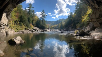Tranquil river scene under a natural rock archway, showcasing autumnal colors and calm water reflections.