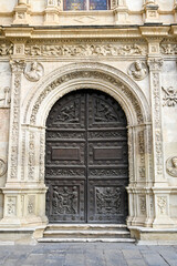 The renaissance wooden door with Latin inscriptions on the Plateresque facade of Seville Town Hall.