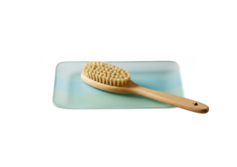 Natural bristle body brush with wooden handle resting on a light blue rectangular pad isolated on transparent background