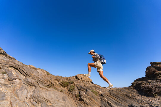 tourist girl with a backpack on her back climbs the mountain in summer - Powered by Adobe