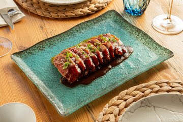 Top view of tuna tataki with sauce in luxury wooden interior restaurant with diffuse light