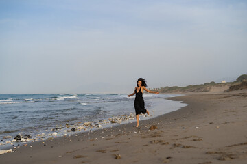 Brunette Woman in Black Dress Running on the Beach