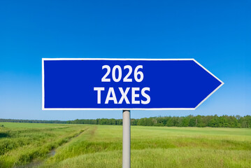 2026 taxes new year symbol. Concept words 2026 taxes on beautiful blue road sign. Beautiful green grass field forest and blue sky background. Business and 2026 taxes new year concept. Copy space.