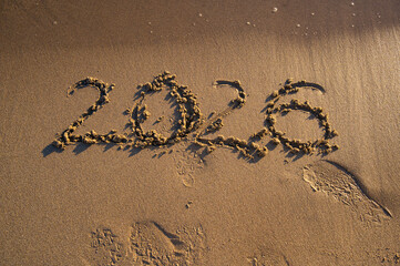 The year “2026” written on sandy beach near the shoreline