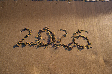 The year “2026” written on sandy beach near the shoreline