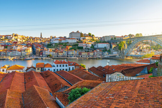 Panoramic view of Porto city Ribeira district with red rooftops, Douro River and Dom Luis Bridge at sunrise, Portugal. Oporto old town with Portuguese architecture. Travel and tourism in Europe