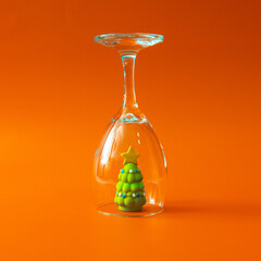 Minimal composition with Christmas tree under upside-down glass on orange background. Creative winter concept. Modern holiday still life with conceptual meaning.