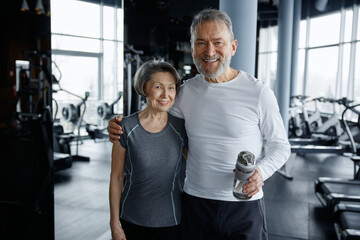 A man and a woman are happily posing for a picture together in a gym