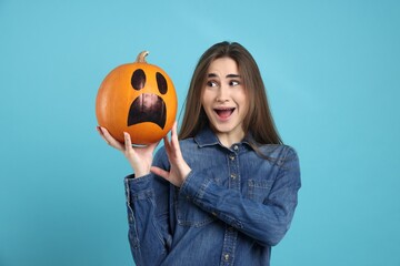 Happy Halloween. Woman with Jack-o'-lantern pumpkin on light blue background