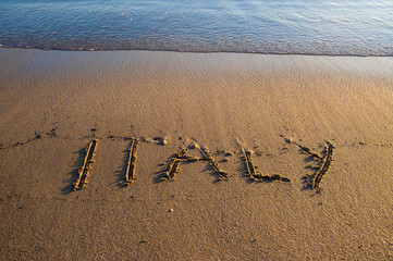 The word “ITALY” written on sandy beach near the shoreline