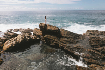 Woman Standing on Coastal Rocks by the Ocean