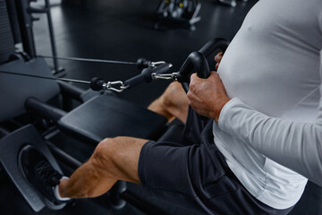 Senior man performs rowing exercise at modern gym