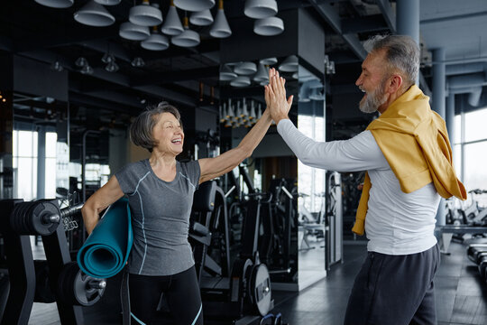 Two elderly people are enjoying their gym day, sharing a high-five - Powered by Adobe