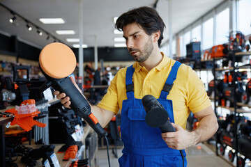 A man worker is holding a polisher in a store