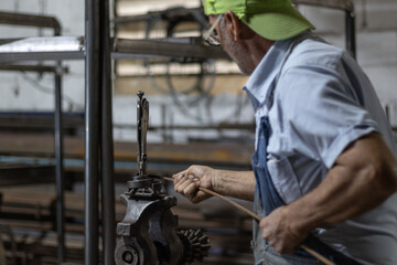 Blacksmith bending metal rod in workshop, crafting ironwork, working with traditional artisan tools