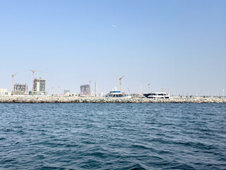 Seafront apartment buildings under construction with cranes, scaffolding. Waterfront real estate development concept.