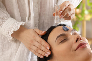 Fototapeta premium Woman undergoing crystal therapy to heal or restore her aura indoors, closeup