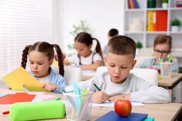 Obraz premium Children at wooden desk during art lesson in elementary school