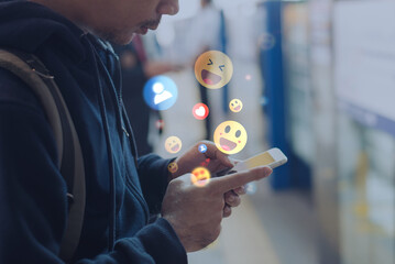 Person using smartphone with floating social media emojis and reactions, representing online communication, engagement, and digital interaction in modern life.